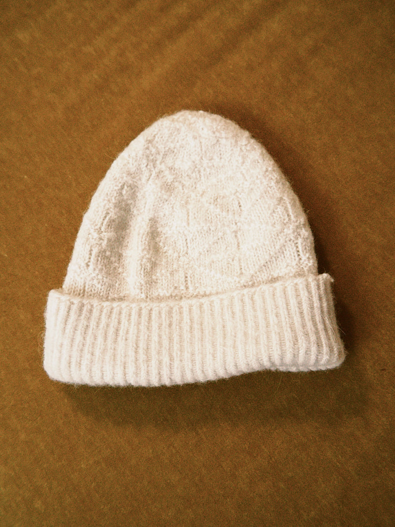 White knit alpaca wool beanie on a velvet background