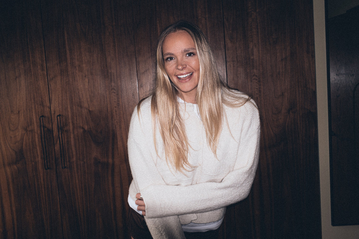 Woman wearing a Cream Alpaca Wool Cardigan standing against a wooden wall.