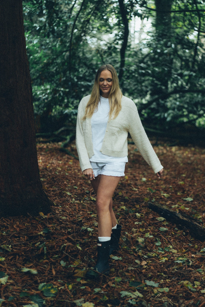 Woman walking through a forest wearing a Cream alpaca wool cardigan