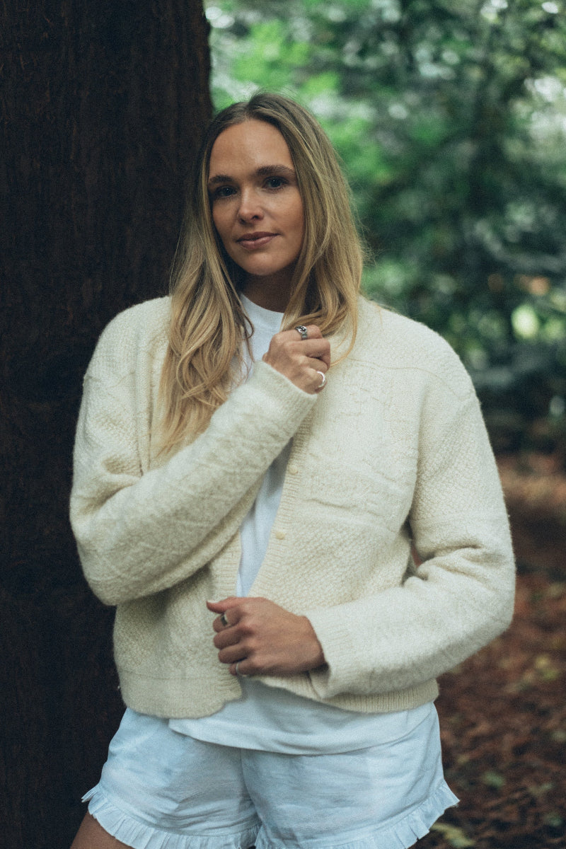 Woman wearing a Cream alpaca wool cardigan in a forest setting