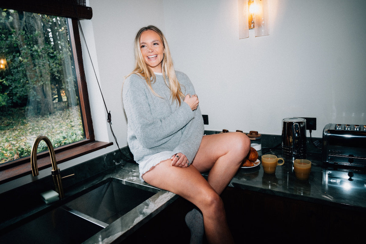 Woman sitting on a kitchen counter in a Grey textured alpaca wool jumper
