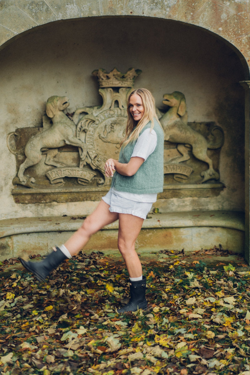 Woman standing in a Mohair pointelle knit vest with autumn leaves on the ground.