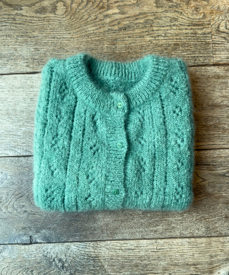 Folded green sweater on a wooden surface