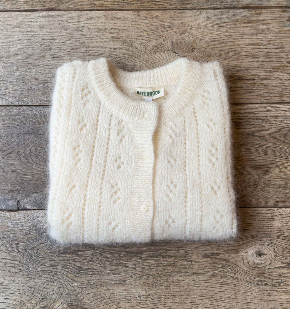 Folded Mohair pointelle knit vest with a brand label on a wooden surface