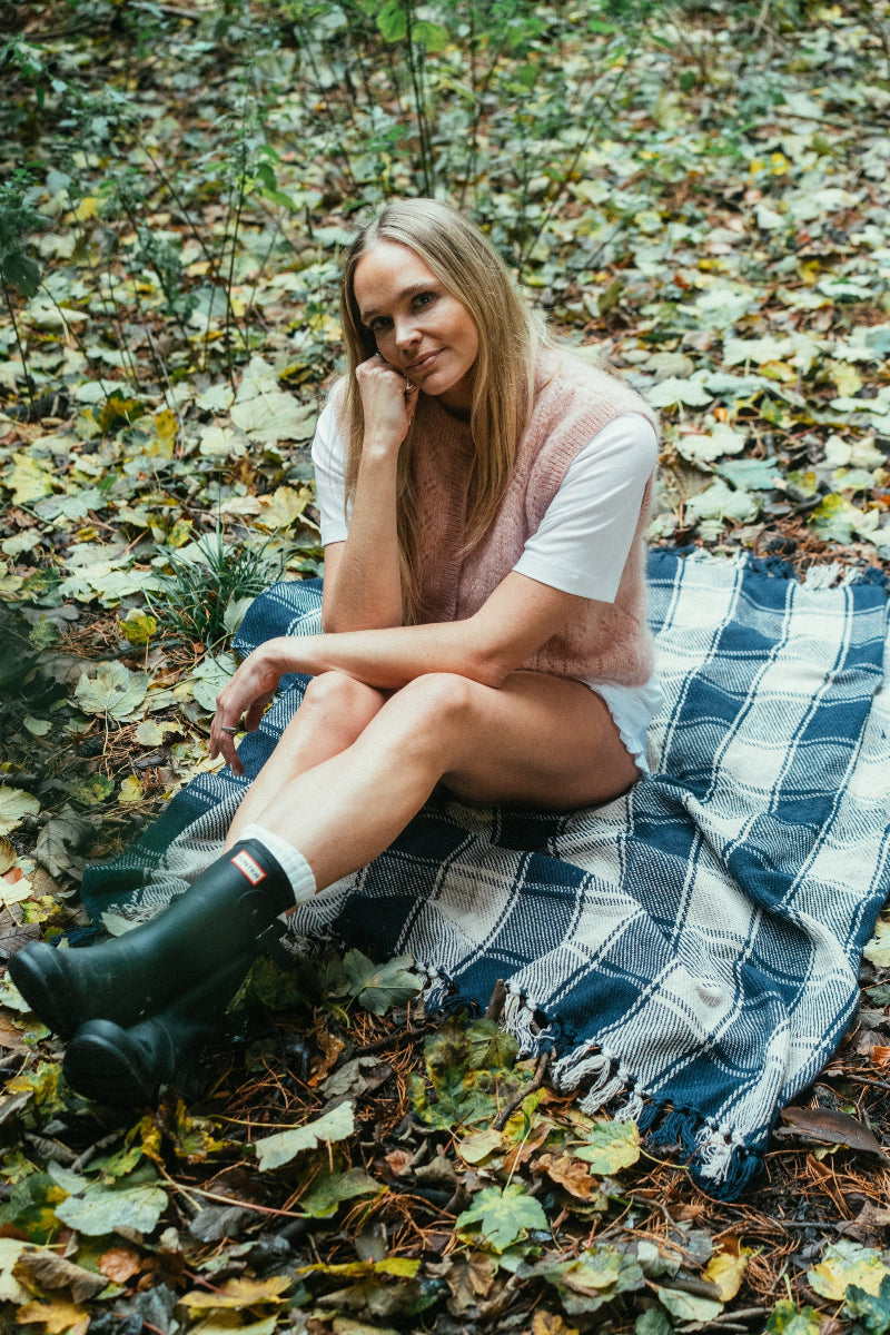 Woman sitting on a plaid blanket in a Mohair pointelle knit vest in a forest with fallen leaves