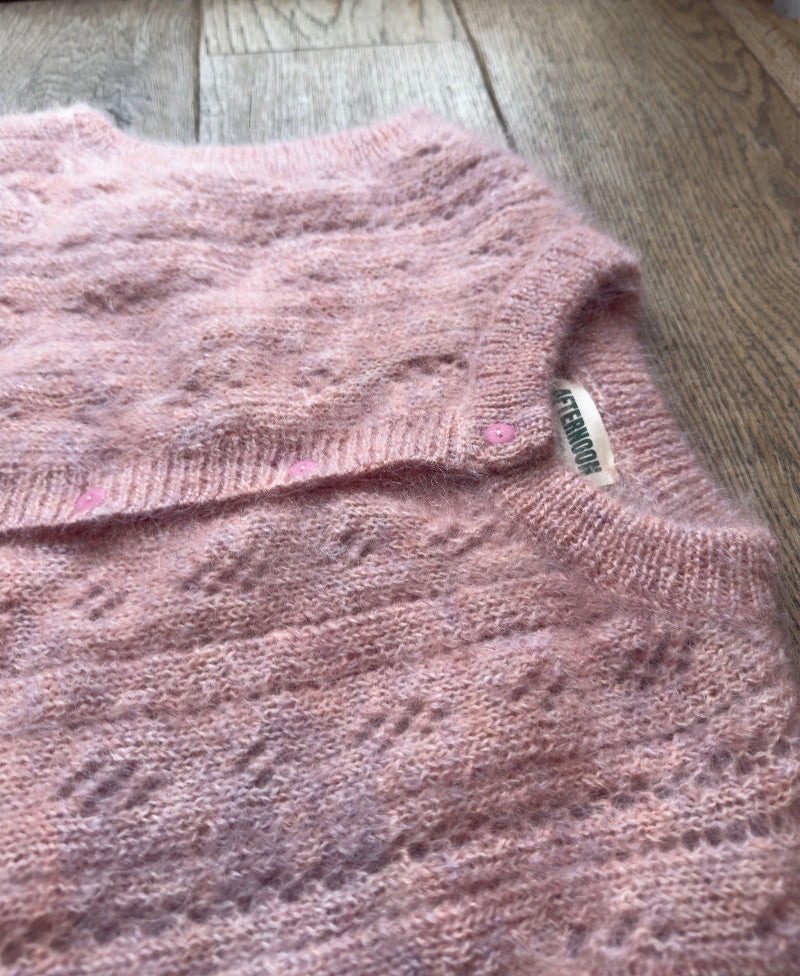Pink Mohair pointelle knit vestwith a brand label on a wooden floor