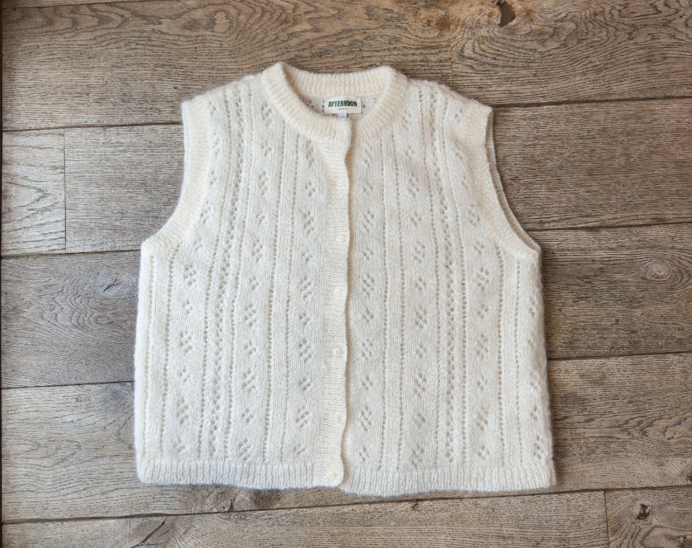 White knitted mohair vest on a wooden surface